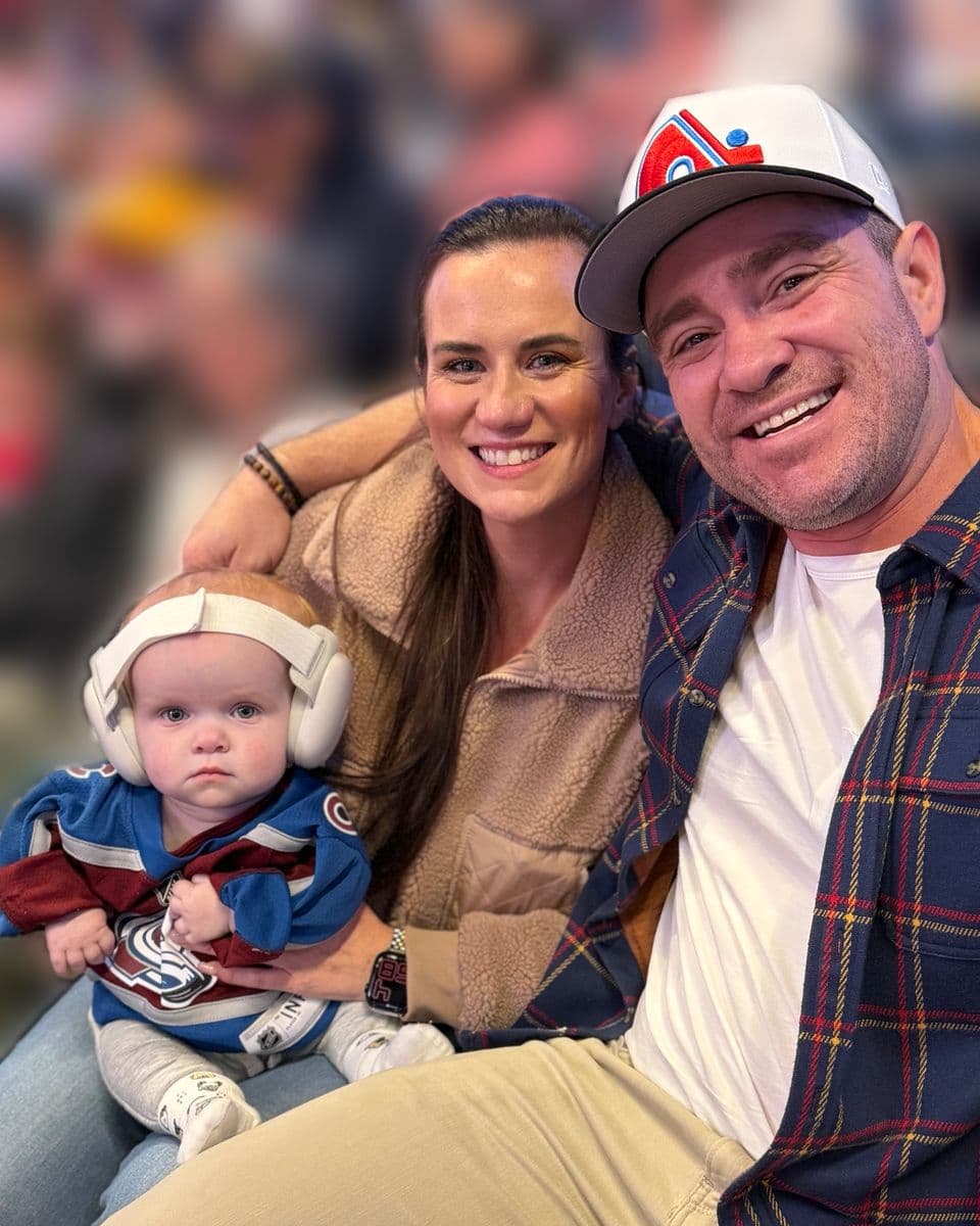 Andrew Brough with his wife and baby at a hockey game